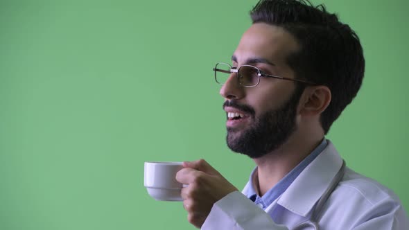 Closeup Profile View of Happy Young Bearded Persian Man Doctor Drinking Coffee