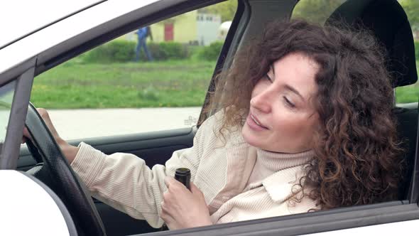 Woman is Drinking Wine While Sitting in Her Car