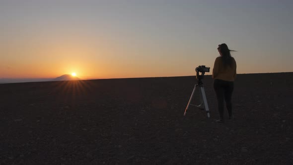 Cinematic view of woman filming sunset