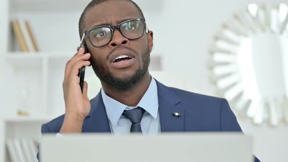 Portrait of African Businessman with Laptop Talking on Smartphone 