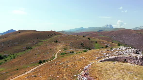 Aerial View of Arid Country Land Some Green Bushes and Trees Blue Sky Mountain in the Horizon Dirty