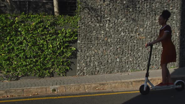 Mixed race woman riding electric scooter on street