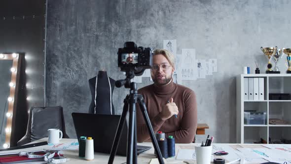 Young fashion blogger is recording video blog about design of clothes using camera.