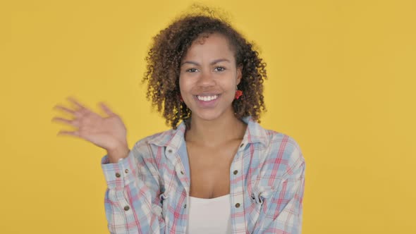 Young African Woman Waving Welcoming on Yellow Background