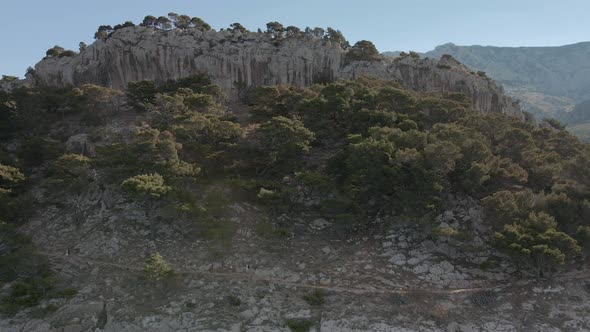 A Group of People Follow a Path Over a Cliff