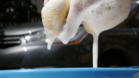 Hand holds sponge for manual car wash slow motion footage