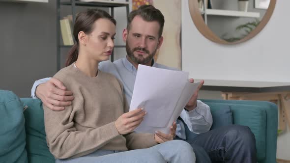 Couple Celebrating Success While Reading Documents on Sofa