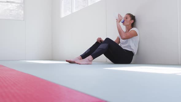 Caucasian woman drinking water after training