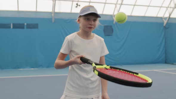 Young Girl Doing Tennis Ball Hits Exercise On Court