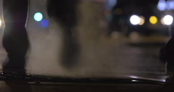 People walking over steaming drain in night city