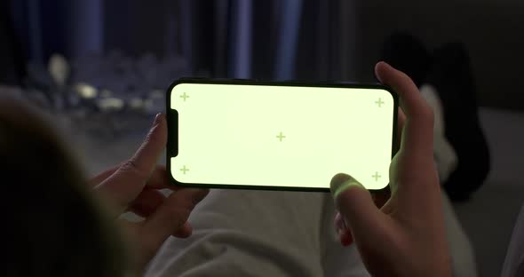 Woman Rests on the Sofa and Uses Smartphone Scrolls Through the Images and Swipe Across the Green