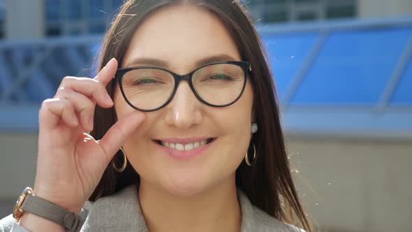 Closeup of a Young Woman Straightening Glasses and Smiling at the Camera