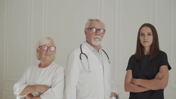 Team of Medical Professionals Lead By Senior White Haired Doctor Looking at Camera