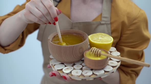 Cropped View of Woman Mixing Honey with Lemon on White Background