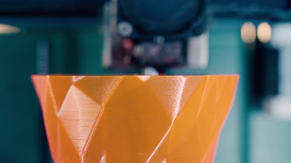 Printing Mechanism Is Adding Layers To an Orange 3D-object. Three Dimensional 3d Printer Working at