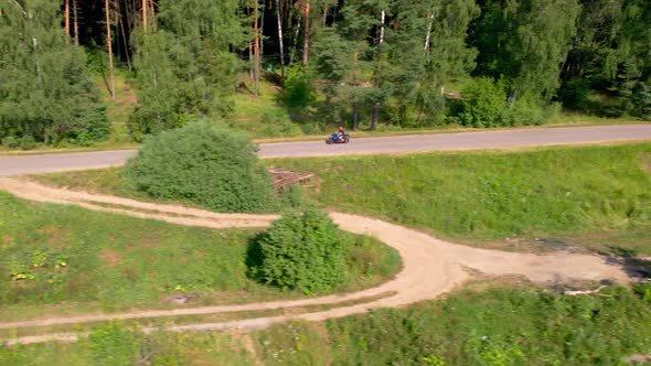 A Young Man Rides a Motorcycle Outside the City