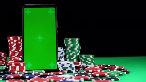 Close-up of Chroma Key Mobile in Vertical Orientation Among a Pile of Poker Chips