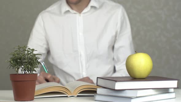 Young Man Studying With Stack Of Books And Apple As Symbol Of Knowledge