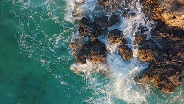 Aerial Top View Of Sea Wave Hitting Cliffs Of A Rocky Coast