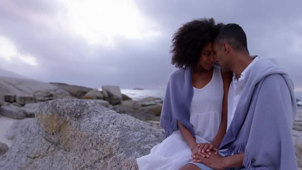 Couple wrapped in blanket on beach 4k