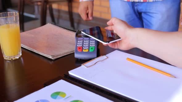 A male customer pays using NFC contactless payment technology on a smartphone.