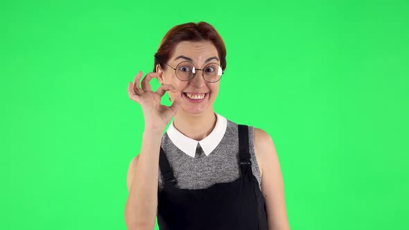 Portrait of Funny Girl in Round Glasses Is Making Sign Ok. Green Screen