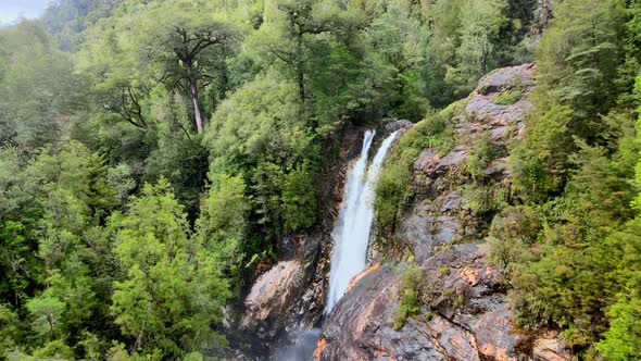 Dolly out aerial view of the Rio Blanco waterfall surrounded by the vegetation of the Hornopiren Nat