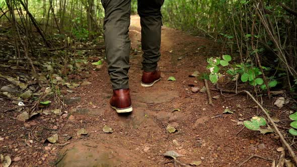 slow-motion of hiking man with trekking boots walking in the natural forest