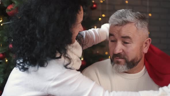 Woman Putting Santa Hat on Her Handsome Husband at Christmas