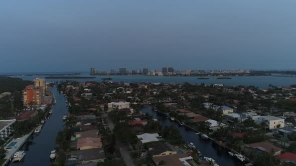 Aerial shot flying near houses in North Miami with buildings on the coast in the background