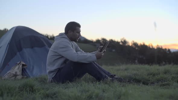 Young Man Using Tablet in Nature Mountain Outdoor at Sunrise or Sunset Dolly