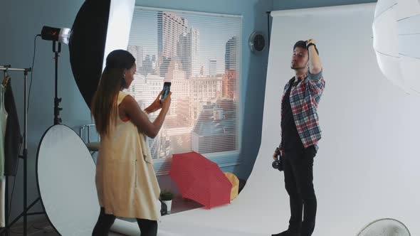 Young African Woman Taking Photos of Smiling Photographer in Casual Clothes on Smartphone