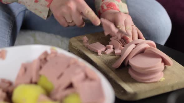 Woman cut doctor's sausage with small sharp knife into small cubes