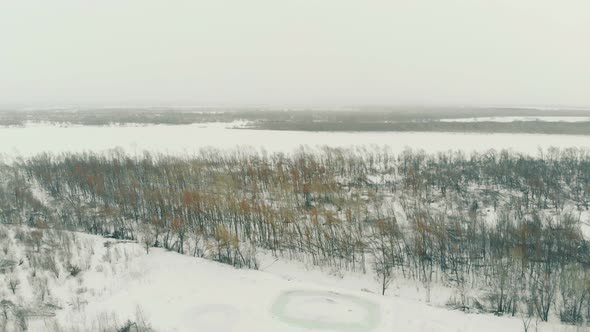 Snowy Mountain at Bare Forest and Frozen River Aerial View