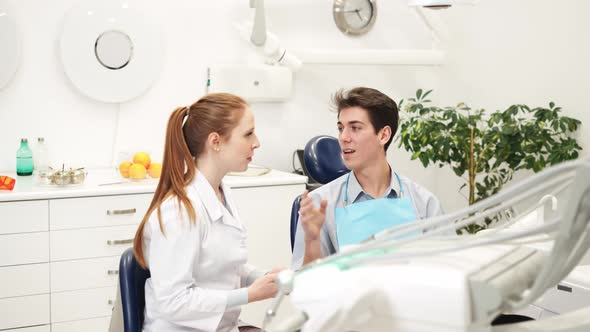 Professional Female Dentist with Digital Tablet in Hands Discussing Treatment with Male Patient