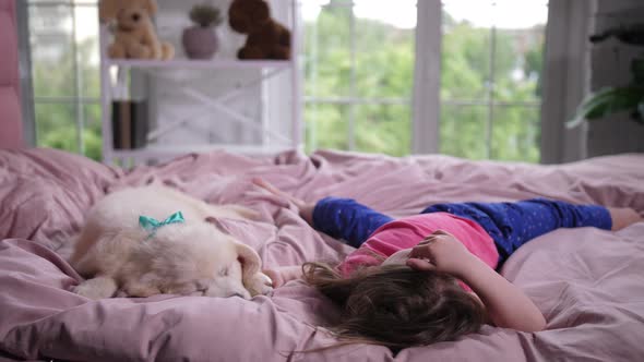 Sweet Little Girl Cuddling Sleepy Puppy in Bed