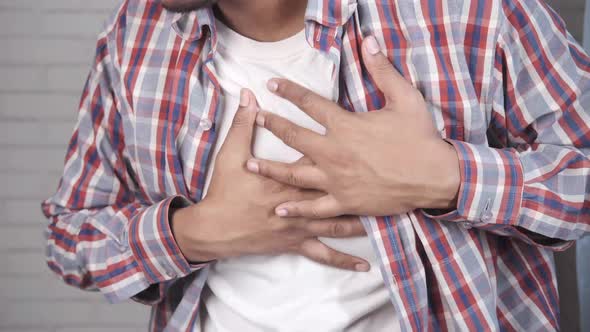 Young Man Suffering Pain in Heart and Holding Chest with Hand