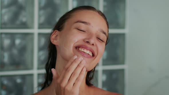 Happy Woman Caring For Face Applying Cream Moisturizer In Bathroom