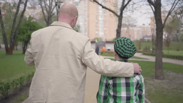 Portrait Back View of Grandfather and Grandson Walking in the Park with Their Backs To Camera