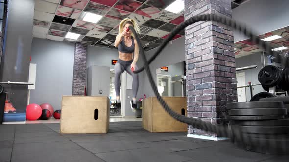 Young sporty woman working out with Fitness battling ropes at gym