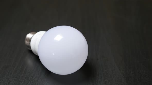 Classic bulb contemporary LED bulb alternative on  wooden table slow tilt 4K 2160p 30fps UltraHD foo