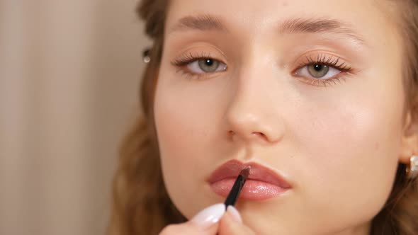 Make-up of a Young Girl's Face. Applying Paint To the Lips of the Girl