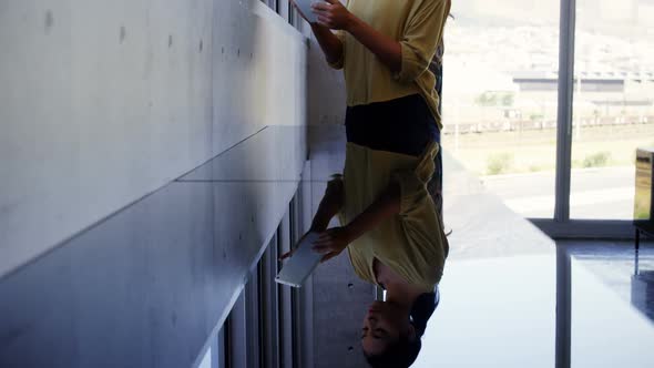 Executive standing near window and using digital tablet