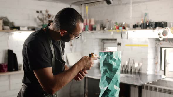 Male craftsman burns his product with a gas burner in the workshop