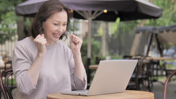 Old Woman Celebrating Success on Laptop While Sitting Outdoor