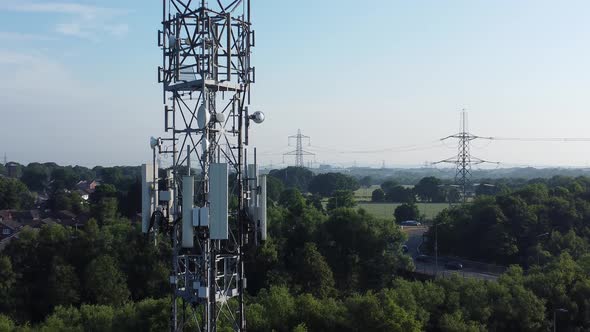 5G broadcasting tower antenna in British countryside with vehicles travelling on highway background