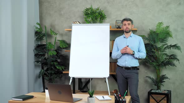 Man teacher stands near whiteboard listens student teaches remote video call