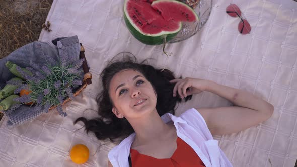 Top View Portrait of Relaxed Smiling Beautiful Young Woman Lying on Blanket with Watermelon and