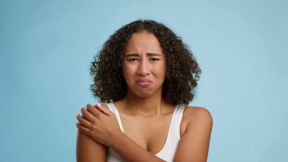 Unhappy Black Young Female Massaging Aching Shoulder Over Blue Background