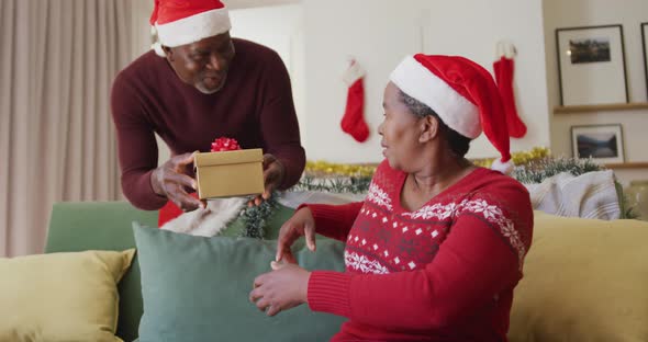Happy senior african american man giving gift to his wife